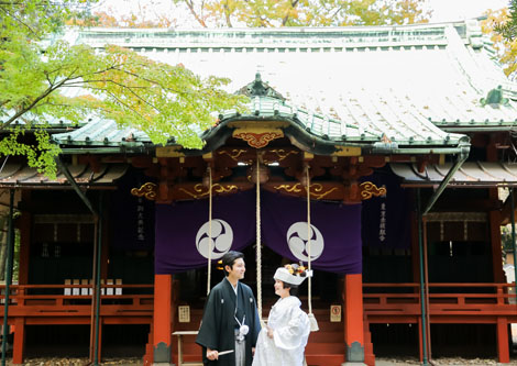 神社の前で互いの顔を見る新郎新婦