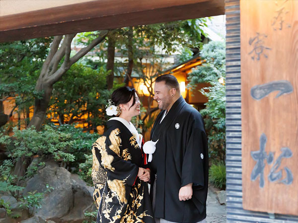 浅草の料亭「茶寮一松」の看板前で向かい合う和装の新郎新婦