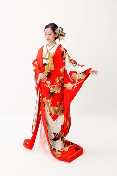 金色の梅と白い鶴の柄の赤い色打掛を着て、片手を広げる花嫁
