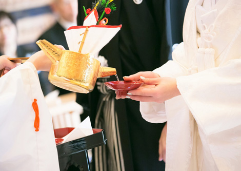 巫女が花嫁のお猪口にお神酒を注ぐ