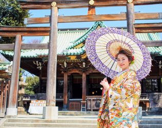和傘を指し浅草神社の鳥居に立つ着物姿の女性