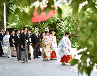 巫女の後を歩いて行く新郎新婦とその家族