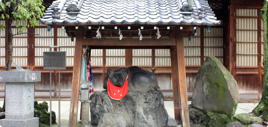 赤い前掛けをかけた牛島神社の撫牛