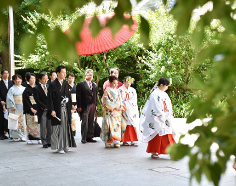 巫女の後を歩いて行く新郎新婦とその家族